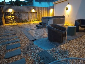 Un jardin avec un jacuzzi, un espace salon extérieur et un chemin en pierre.