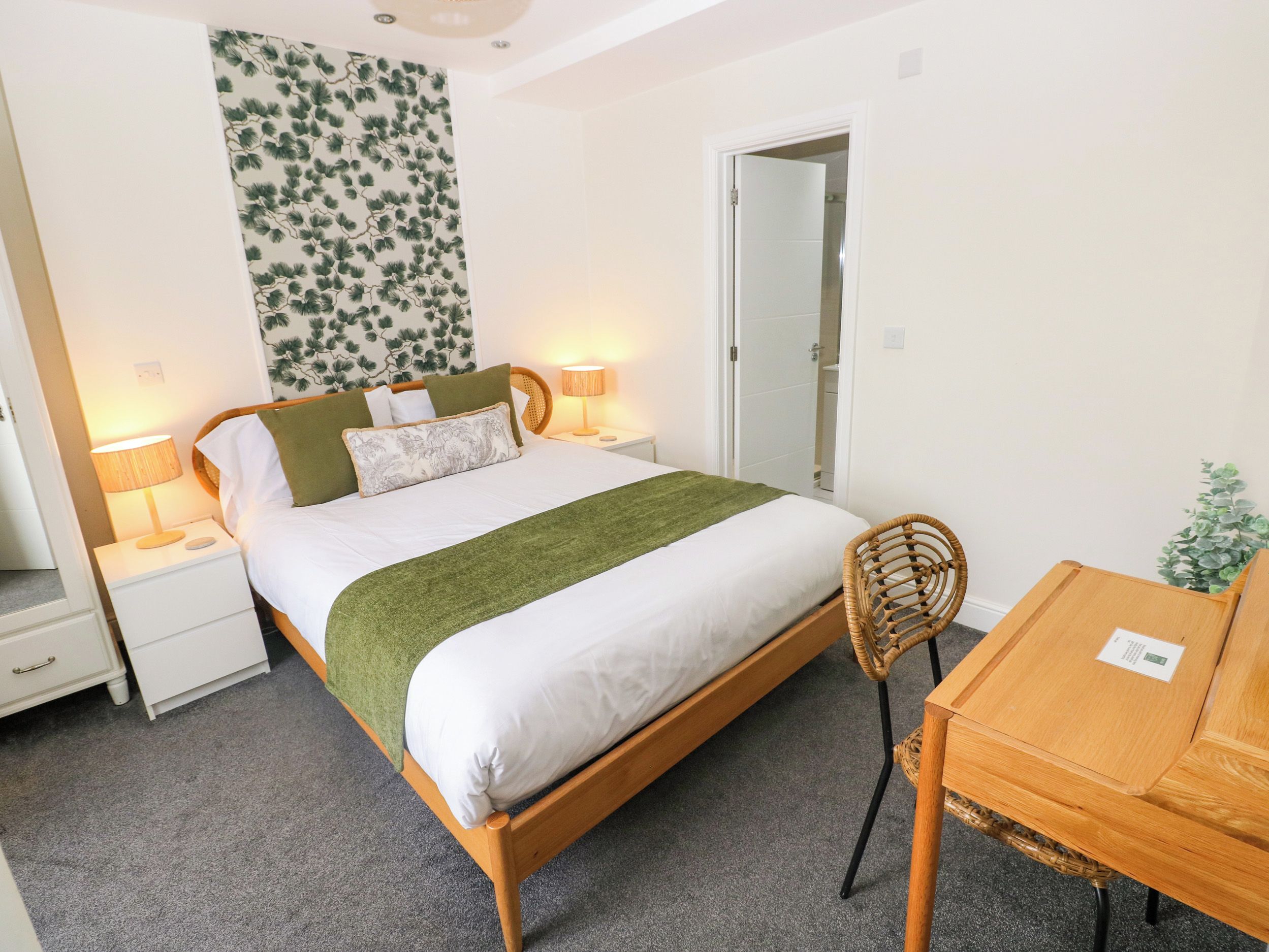 A neatly arranged bedroom with a bed, bedside lamps, a chair, and a small table.