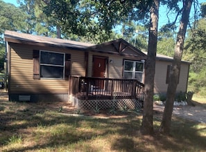 A single-story mobile home with a front porch, a small deck, and a front door. - 2-bedroom house on 5 acres in delightful Smithville with cool AC breeze (Smithville)