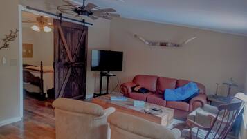 A living room with a television, a sofa, a coffee table, and two armchairs.