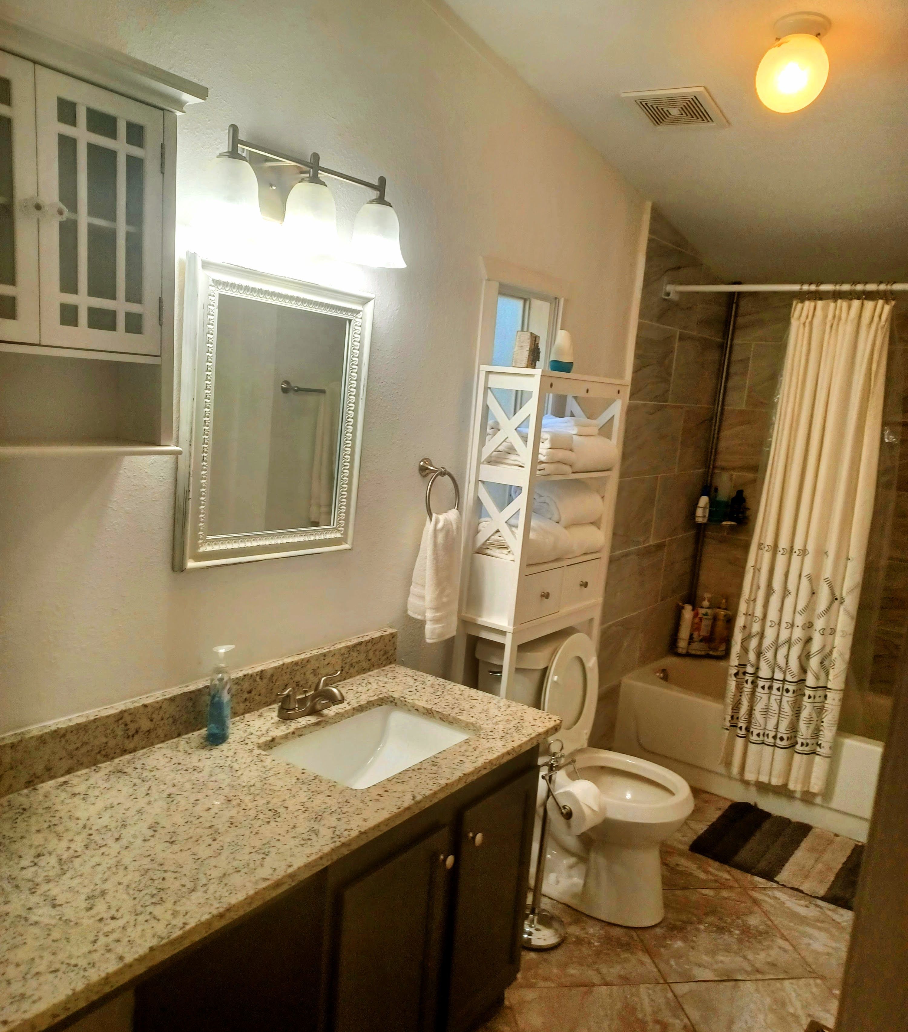 A bathroom with a sink, toilet, and shower area.