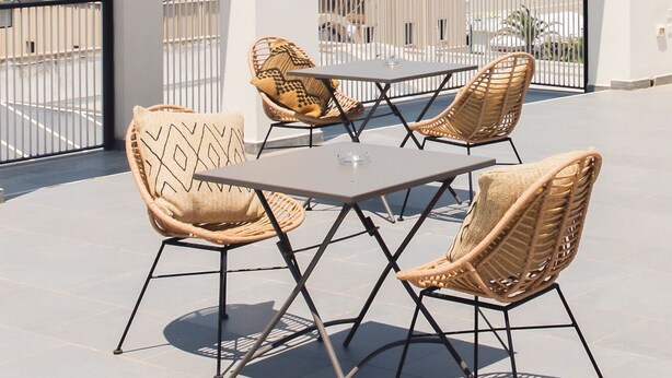 Ein Balkon mit Korbstühlen und einem Tisch, mit Blick auf einen Strand und das Meer.