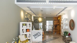 Ein modernes Interieur mit einer Rezeption, einer Wand mit Holzapplikationen und einer Sitzecke mit gelben Stühlen.
