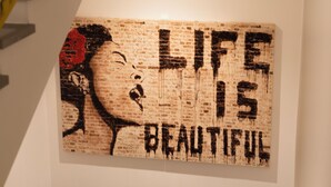Ein Wandbild mit der Aufschrift „LIFE IS BEAUTIFUL“ in einer abgenutzten Schriftart.