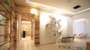 Eine moderne Hotelhalle mit Holzvertäfelung, einem weißen Dekobuchregal und einer Rezeption.