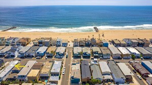 A coastal RV park with rows of RVs and cabins, a beach in the background, and a clear sky. - Peek-A-BOO ocean view. 50 Steps to the Sand Large Remodeled Beach House.  (Newport Beach)