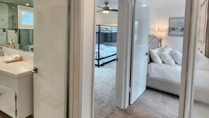 A modern hotel room with a bathroom, a bedroom with a bed and a nightstand, and a hallway leading to another room. - Peek-A-BOO ocean view. 50 Steps to the Sand Large Remodeled Beach House.  (Newport Beach)