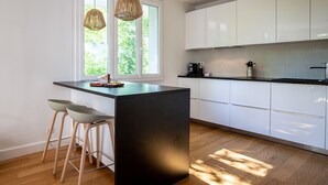 Una cocina moderna con una isla central, armarios blancos y un amplio ventanal que proporciona luz natural.