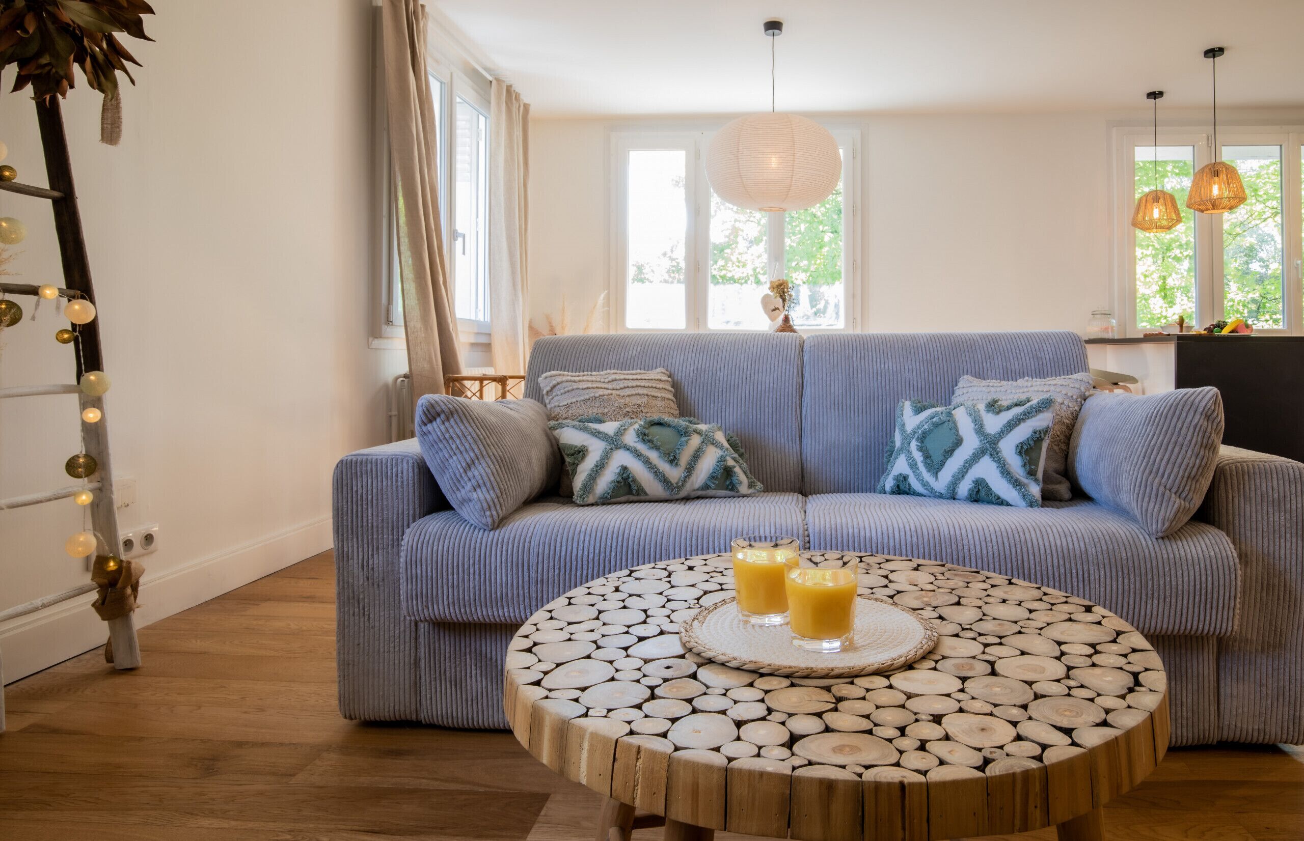 A living room with a blue sofa, round wooden coffee table, and two glasses of orange juice.