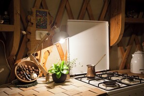 Een keuken met een gasfornuis, een schaal met noten, een bloempot en een witte koelkast.