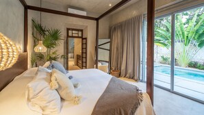 A bedroom with a large bed, a bedside table, a hanging light fixture, and a view of a swimming pool. - The Horseshoe - spacious pool & sunset roof terrace (Mérida)