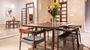 A dining area with a wooden table and chairs, a vase with flowers, and pendant lighting. - The Horseshoe - spacious pool & sunset roof terrace (Mérida)