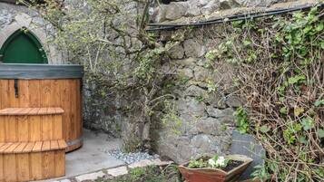 A stone wall, a wooden bench, and a wooden planter with white flowers.