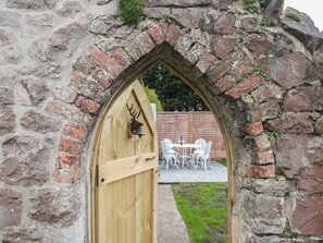 A stone archway leading to a wooden door with a deer head knocker. - The Hideaway (Weston-super-Mare)