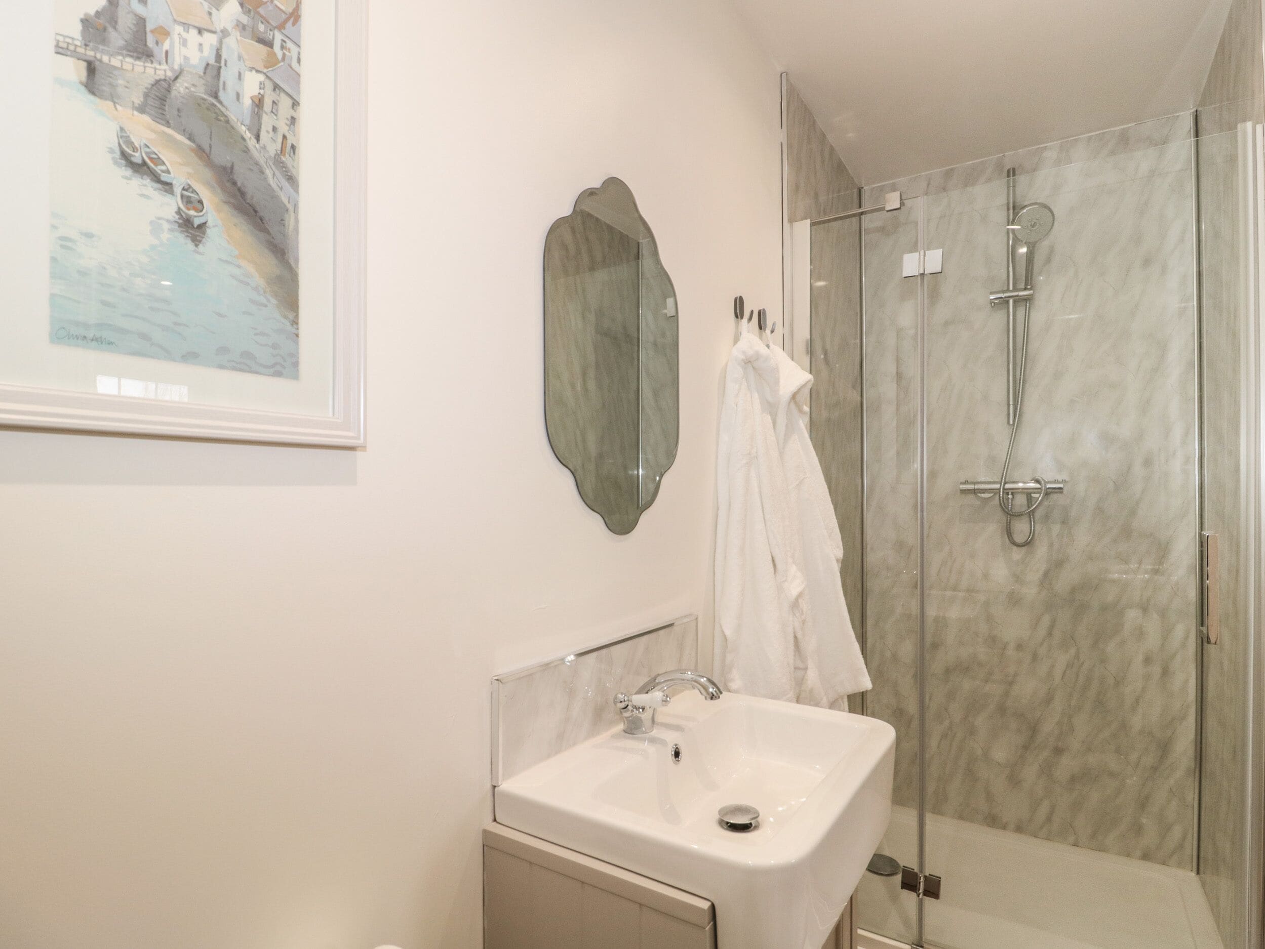 A modern bathroom with a sink, mirror, and glass-enclosed shower.