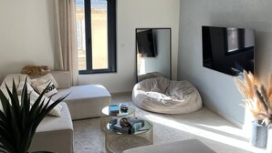 A modern living room with a sofa, a bean bag, a coffee table, and a TV mounted on the wall.