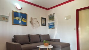Ett vardagsrum med en brun soffa, ett litet vitt bord med en växt och flera inramade konstverk på väggarna.