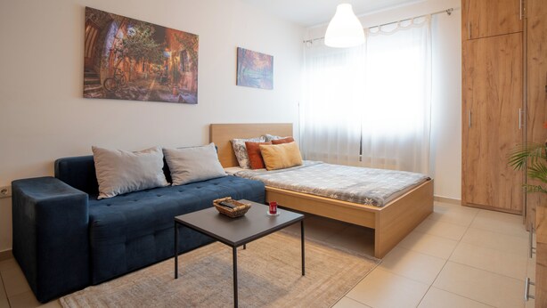 Ein modernes Schlafzimmer mit einer Couch, einem Bett und einem kleinen Tisch.