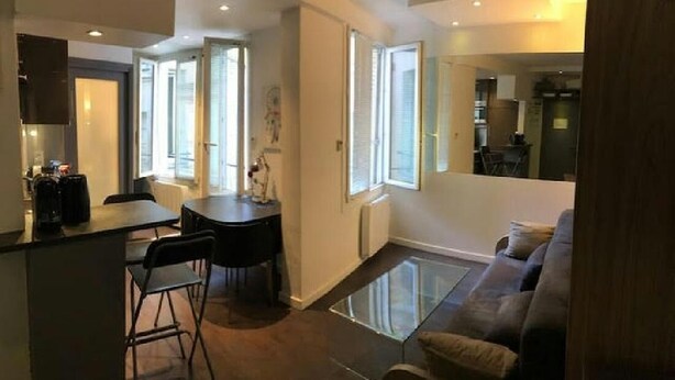 Una sala de estar moderna con una mesa de centro de vidrio, un sofá y un comedor con mesa y sillas.