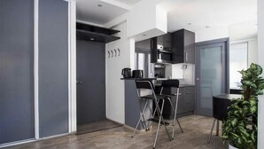 Una cocina moderna con zona de comedor, que incluye una mesa y sillas plegables, una cafetera y una planta en maceta.