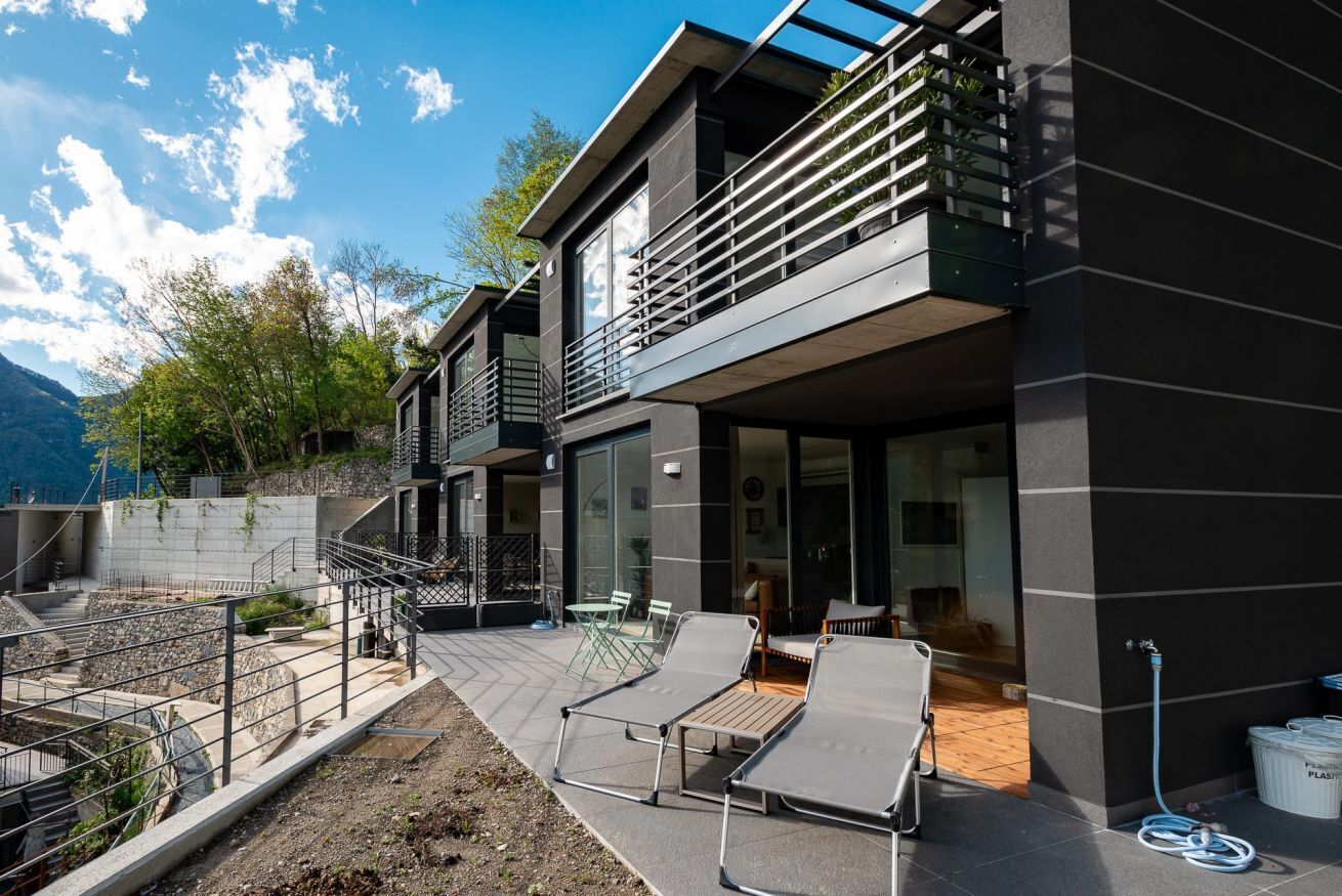 Een modern gebouw met twee verdiepingen, een balkon, een terras en uitzicht op de bergen.