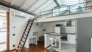 Een appartement in loftstijl met een keuken, een eethoek en een trap.
