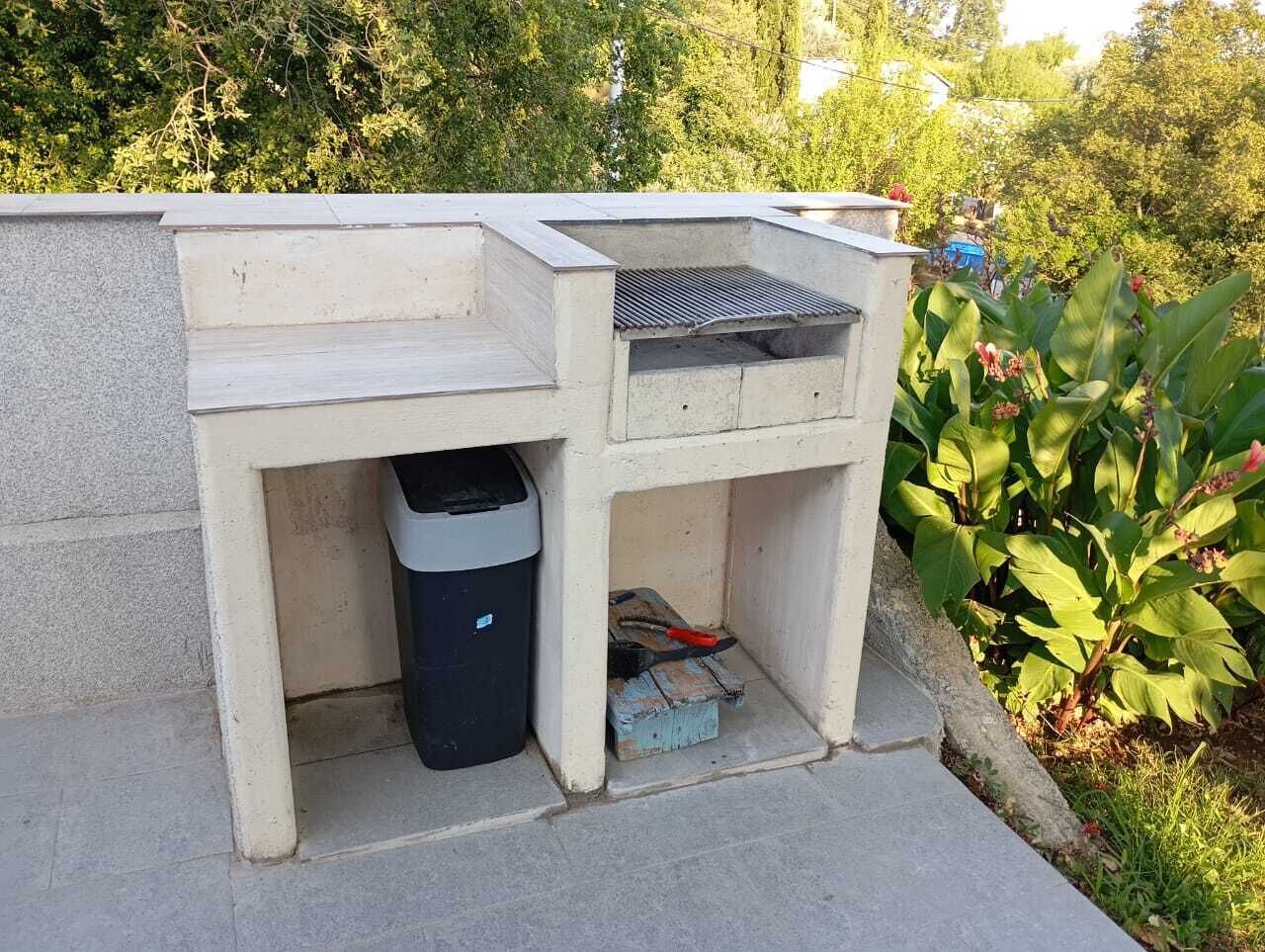 Un espacio de trabajo al aire libre de hormigón con un cubo de basura y un pequeño cofre de almacenamiento.