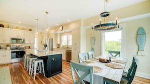 A spacious kitchen with a central island, wooden flooring, and a dining area with a table set for four.