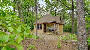 A small, single-story building with a stone facade and a tiled roof, surrounded by trees. - Blissful Broken Bow Studio: Fire Pit & Jacuzzi Tub (Broken Bow)