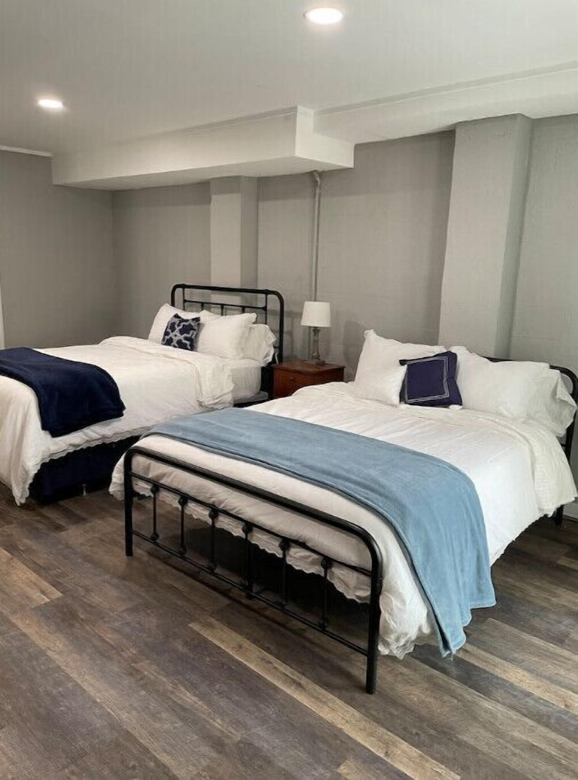 A room with two beds, a nightstand, and a lamp.