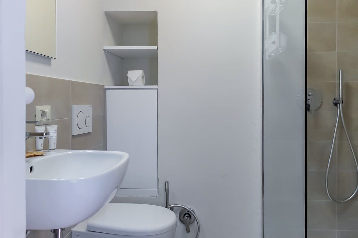 A modern bathroom with a white sink, toilet, and glass shower enclosure.