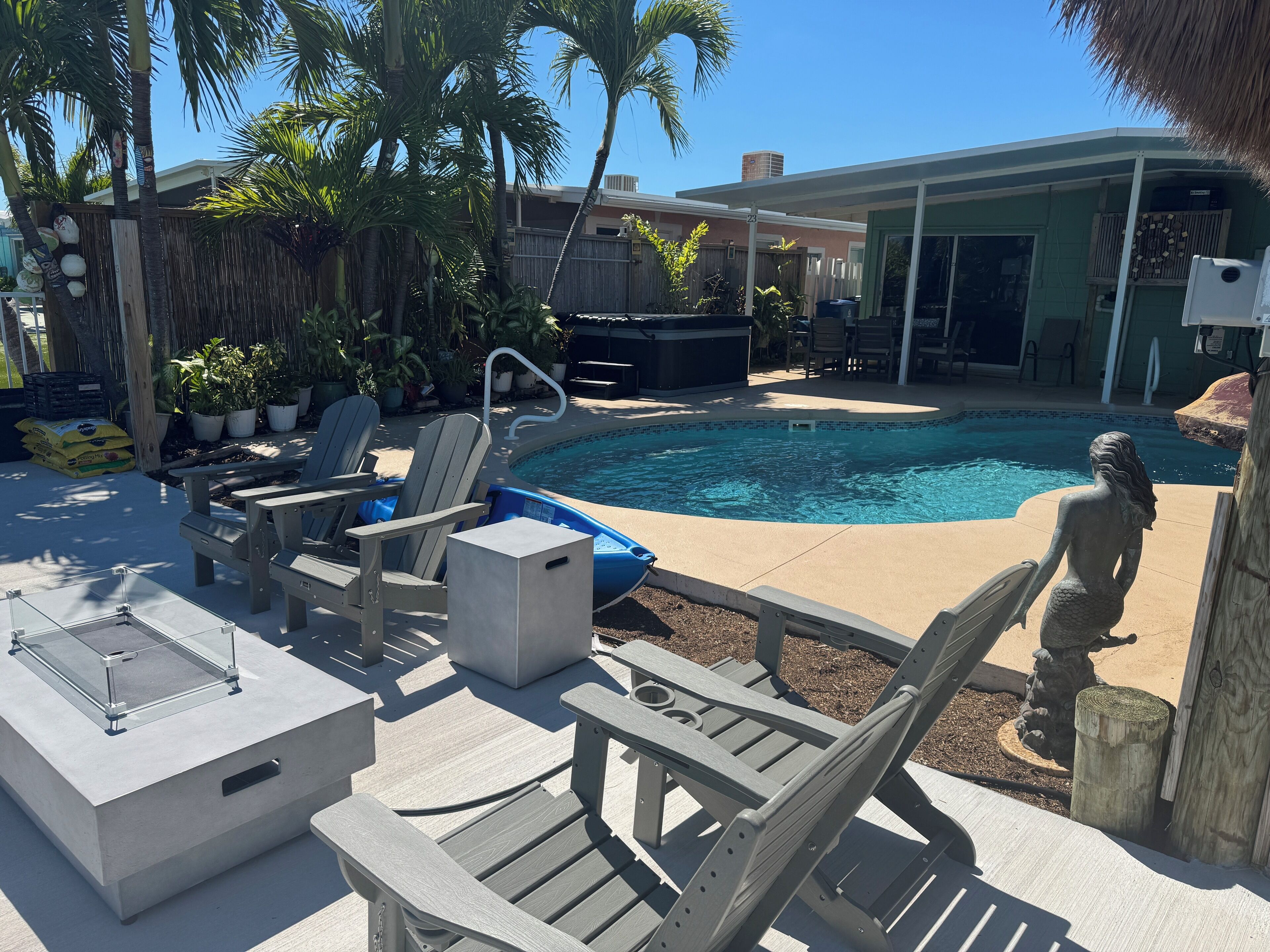 A backyard with a swimming pool, lounge chairs, and a statue.