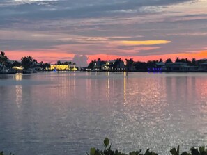 Un lac paisible au crépuscule, avec des bâtiments dont le reflet se mire dans l’eau.