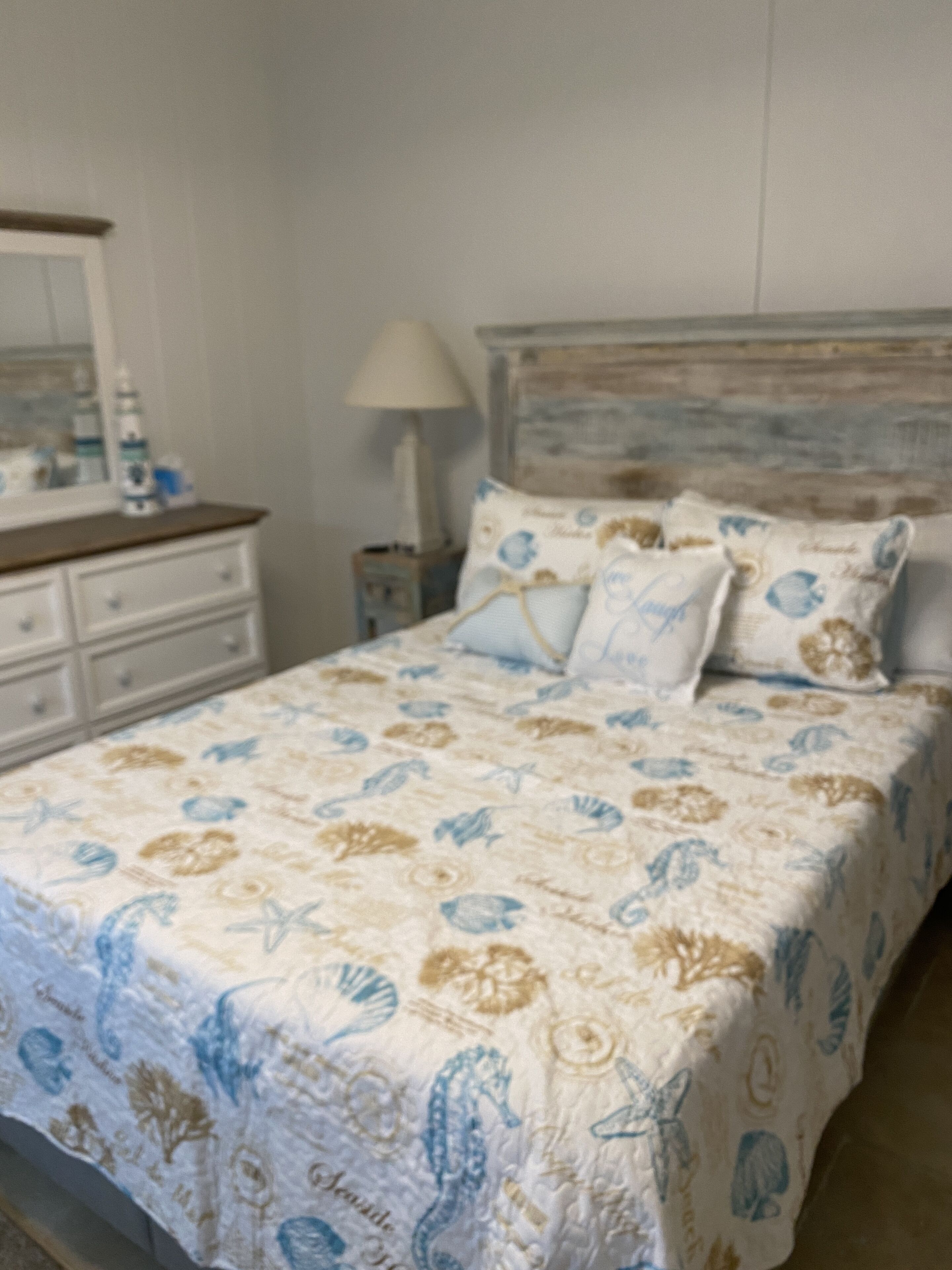 A bedroom with a bed, a nightstand, a dresser, and a lamp.