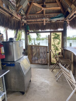 Un espace extérieur doté d’un toit de chaume, d’un barbecue, d’un extincteur et offrant une vue sur l’eau.