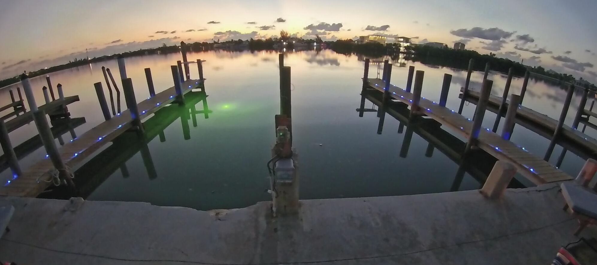A waterfront view with a dock and calm water reflecting the sky.