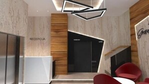 A modern reception area with a reception desk labeled "RECEPTICA," a black elevator, and red chairs. - Hotel Grand (Banja Luka)