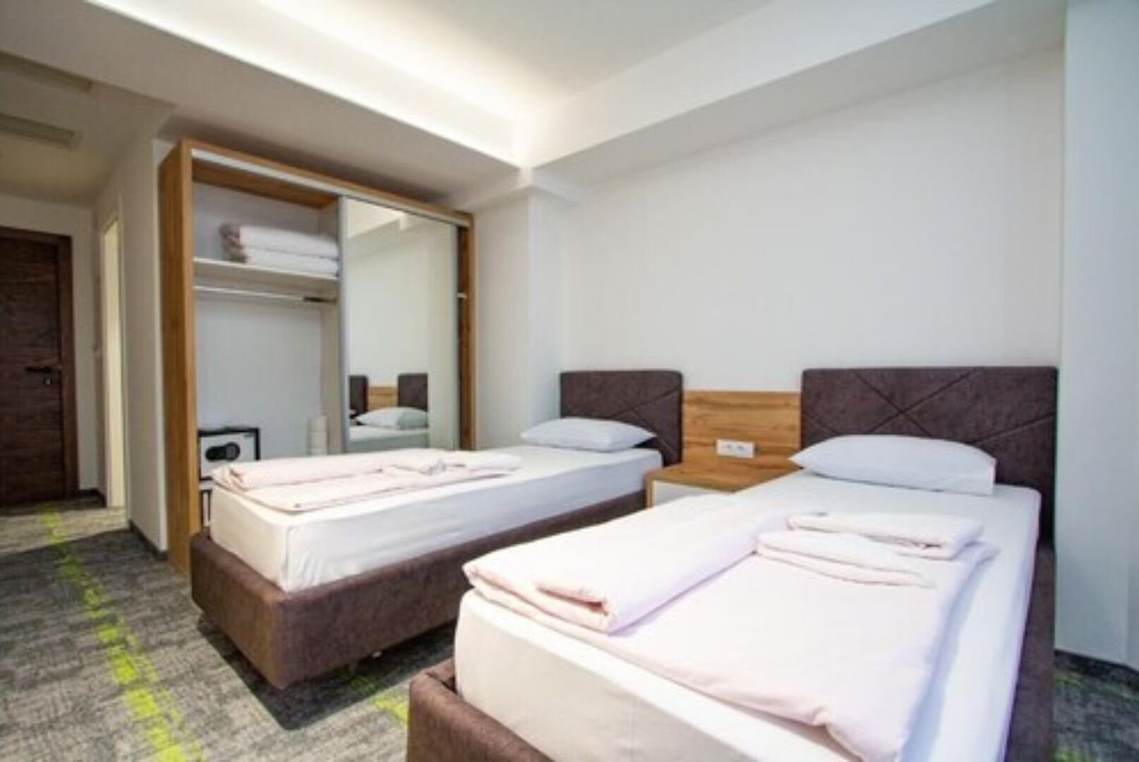 Een hotelkamer met twee enkele bedden, een kledingkast en een spiegel.