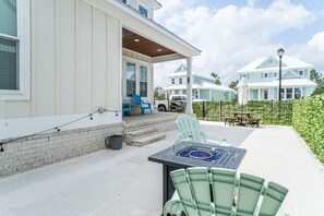 A covered outdoor area with a table and chairs, a barbecue grill, and a patio with steps leading to a covered porch.