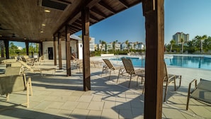 An outdoor pool area with lounge chairs and a covered seating area. - Luxury 4BR/4BA Beach Retreat Game Room, Resort Pool, & Prime Location (Orange Beach)