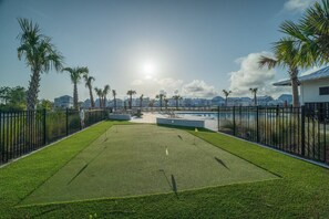 A well-maintained golf course with a clear path, palm trees, and a pool area.