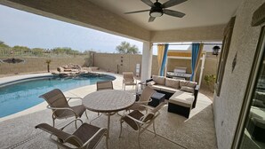 Un patio couvert avec une piscine, du mobilier d’extérieur et un barbecue.