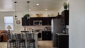 Une cuisine moderne avec des meubles de couleur sombre, des appareils en acier inoxydable et un îlot central doté de tabourets de bar.
