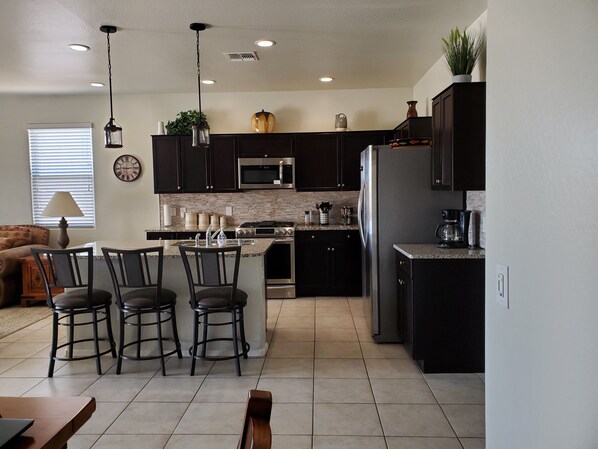 A modern kitchen with dark cabinetry, stainless steel appliances, and a central island with bar stools.