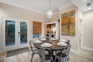 A dining area with a round table set for six, surrounded by metal chairs.