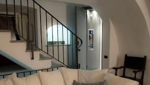Ein Wohnzimmer mit einem weißen Modulsofa, einer Treppe und einem Sessel.