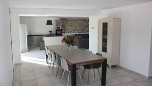 Une cuisine moderne avec un pare-feu en pierre, un coin repas avec une table et des chaises en bois, et un meuble blanc avec des portes en verre.