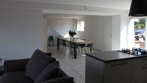 Une cuisine moderne avec un coin repas, un escalier menant à un autre niveau et une vue sur l’extérieur.