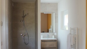 Une salle de bain équipée d’une douche, d’un lavabo, d’une chaise et d’un porte-serviettes.