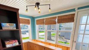 A kitchen with wooden cabinets, a built-in island, a bookshelf, and a view of the outside.